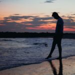 silhouette of a person standing on the beach during sunset