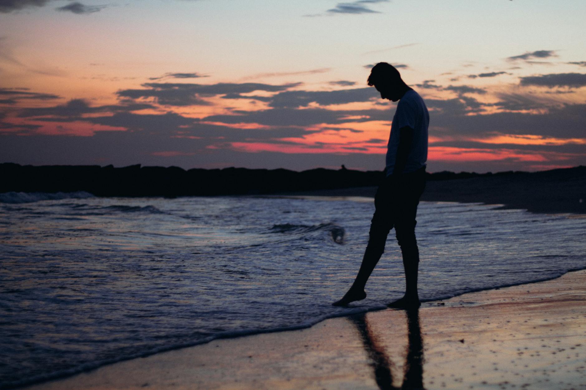 silhouette of a person standing on the beach during sunset